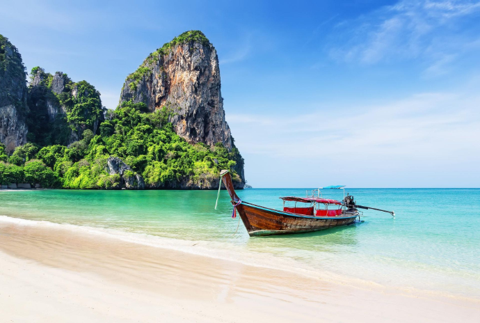 Traditional long tail boat on Krabi beach with limestone cliffs Thailand island tour