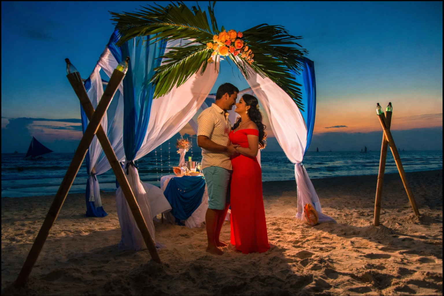 Romantic honeymoon couple under decorated beach arch sunset setup